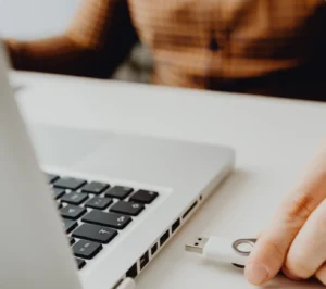 Person jobbar hemifrån med dator och USB